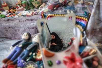 Shireen al-Kurdi, seorang pengungsi Palestina, membuat boneka rajutan untuk dijual menjelang hari raya Idul Fitri, yang menandai berakhirnya bulan suci Ramadhan, di kamp pengungsi Bureij di Jalur Gaza tengah pada 17 Maret 2026. (Foto: AFP)