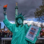 Seorang wanita berdandan seperti Patung Liberty untuk protes 'No King' di Paris, Prancis, pada hari Sabtu (28/3/2026). (Foto: AP Photo/Aurelien Morissard)