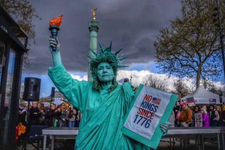 Seorang wanita berdandan seperti Patung Liberty untuk protes 'No King' di Paris, Prancis, pada hari Sabtu (28/3/2026). (Foto: AP Photo/Aurelien Morissard)