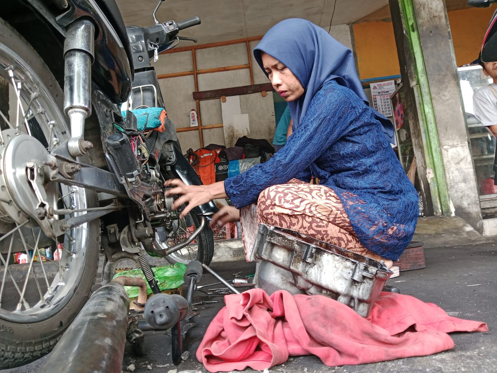 Aksi mekanik perempuan di Banyumas mengenakan kebaya saat bekerja viral di Hari Kartini. Kisah inspiratif ini jadi bukti perempuan mampu menembus batas profesi. (Foto: ReportaseNews/Kus)