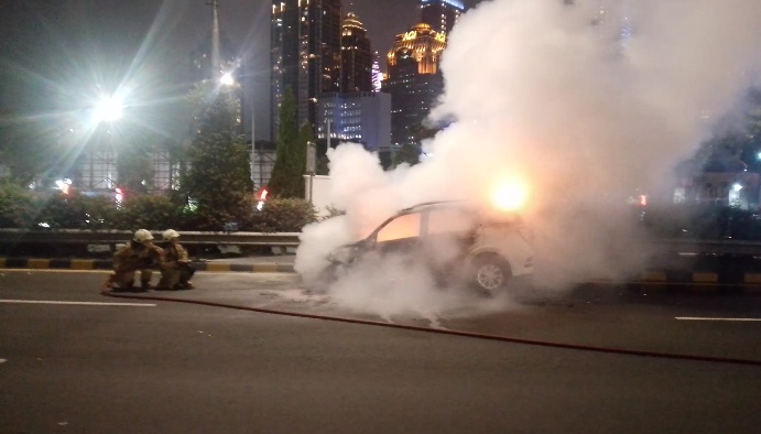 Mobil Terios terbakar di Tol Dalam Kota arah Cawang, Selasa malam. Diduga akibat korsleting listrik, kejadian ini memicu kemacetan panjang hingga 45 menit. (Foto: ReportaseNews/Tama)