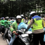 Polda Metro Jaya membagikan sembako dan voucher belanja kepada pengemudi ojek online dalam program Jumat Peduli di Jakarta. Bantuan disambut antusias para driver ojol. (Foto: ReportaseNews/Vira)