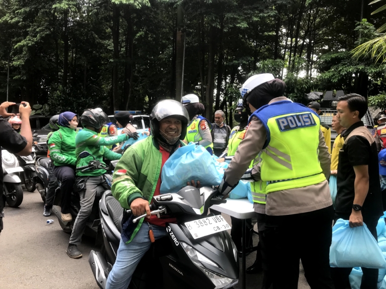 Polda Metro Jaya membagikan sembako dan voucher belanja kepada pengemudi ojek online dalam program Jumat Peduli di Jakarta. Bantuan disambut antusias para driver ojol. (Foto: ReportaseNews/Vira)